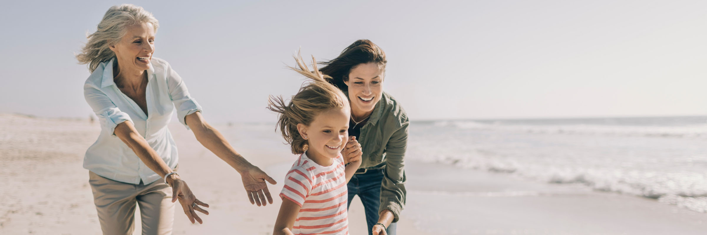 Grandmother, daughter and grandaughter playing at the beach