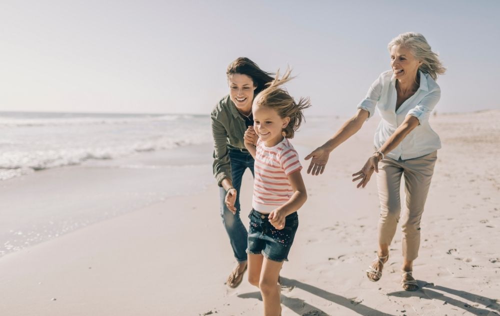 A grandmother, daughter and granddaughter playing on the beach